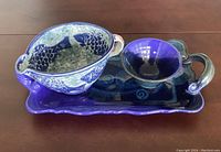 Fish gravy bowl, small bowl, and rectangular tray arranged as a set on a table, showing the fish design on the gravy bowl and deep blue glaze on other pieces.