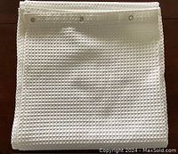 White fabric shower curtain folded showing textured waffle pattern and metal grommets.