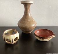 Photo showing all three items: vase, bowl with handle and candle holder arranged on a flat surface