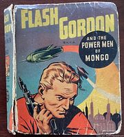 Front cover of the Flash Gordon book showing title, artwork of Flash Gordon, spaceship, and background cityscape. Wear and tear visible on cover and spine.