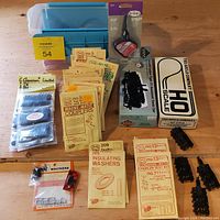 Wide view showing most items: PROTO 2000 tank car kit box, Gould crane kit box, multiple KADEE couplers and accessories, American Limited diaphragms, Testors plastic cement, and small parts box