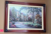 Framed Thomas Kinkade canvas print showing a detailed stone manor house in a lush landscape with a curved driveway and vibrant flora.