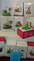 Set of 10 boxed Hallmark Keepsake Christmas ornaments featuring Peanuts Camp Snoopy themes on display.