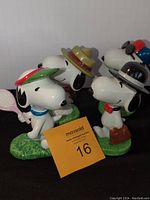 Group photo of all four ceramic Snoopy figures on green grass-like bases.