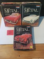 Three Monogram die-cast metal classic sports car model kits in original boxes with colorful vintage artwork showing a '56 T-Bird, a '53 Corvette, and a Jaguar XK120.