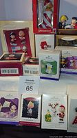 Photo showing multiple boxed Hallmark Keepsake Peanuts ornaments including various characters and holiday themes, boxes mostly intact with printed labels and graphics.
