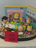 Full view of the Easter Beagle Peanuts figurine showing all characters around the kitchen table with Easter eggs, baskets, and kitchen decor.