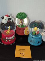 Set of three Peanuts themed snow globes positioned side by side showing all figurines and bases.