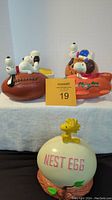 Wide view showing all three ceramic banks featuring Snoopy and Woodstock characters placed in a row: Snoopy on football, Snoopy Flying Ace plane, and Woodstock Nest Egg bank.