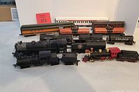 Overview of 12 mixed train model items including locomotives and various cars showing color and condition.