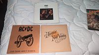 Three vinyl LP albums with covers: ACDC, Spirit, Neil Young laid out on bed.