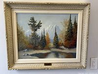 Front view of the framed oil painting showing a Canadian landscape with trees, water, and mountains.