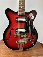 Close-up of body showing pickups, bridge, tremolo arm, f-holes and finish