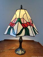 Full view of the floral stained glass lamp lit, showing hexagonal shade and metal base.