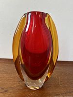 Front view of the vase showing the vibrant red core with encased yellow glass around it and clear glass base.
