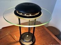 Angled front view showing the glass ring shade with green tint, black metal base and dimmer switch.