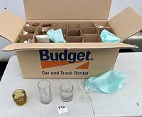 Open box with compartments showing multiple glassware inside, four glasses and one cocktail glass outside the box for display.