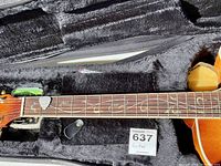 Close view of guitar fretboard showing vine inlays, white guitar pick and clip-on tuner pack