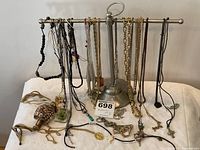 Large collection of assorted costume jewelry necklaces hanging on a metal display stand. The necklaces show various styles, colors, and pendants.
