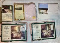 Five queen sheet sets in sealed packaging: two Laura Ashley country roses sets, one Egyptian cotton set, one House & Home microfiber set, one additional Laura Ashley floral set with ribbon
