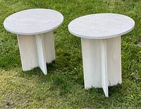 Pair of white homemade wooden tables placed on green grass showing overall design and size difference.