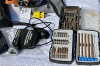 Photo showing Phoenix rechargeable headlamp with black adjustable strap, a Duracell battery charger, and drill bit cases with screw and drill bits.