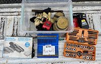 Overall view of tools and hardware including straps in a clear plastic container, Bostik glue gun box, blue drill bit set, and orange tap and die set