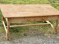 Front side view of vintage wooden coffee table showing single drawer with two knobs and turned legs.