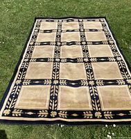 Full view of the wool carpet laid flat on grass, showing the entire geometric pattern and size.