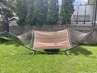 Full view of the double wide hammock outdoors including metal frame and fabric bed with stripes.