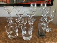 Photo of a variety of clear glass drinkware including martini glasses, coupe glasses, wine glasses and small shot glasses.
