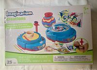 Box of Imaginarium Creations Kids' Pottery Wheel 2-in-1 showing product with clay, paint, and spin wheel for pottery and painting.