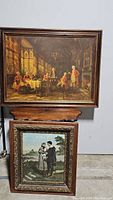 Two paintings stacked, the upper one showing the indoor historical scene, the lower showing the courting couple outdoors in carved wood frames