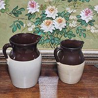 Front view of both McCoy pottery pitchers side by side showing the size difference and design