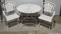Photo showing two white painted wood slatted folding garden chairs with metal frame and round table with wood slatted top and metal frame