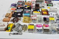 Image showing a table with multiple boxes of staples, screws, measuring tape, and hardware items arranged in rows