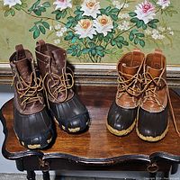 Pair of men's and women's LL Bean Boots showing leather upper with rubber lower waterproof section and lace-up front with yellow laces.