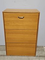 Front view of the wooden shoe cabinet with three closed drawers, showcasing its wood finish and metal handle on the top drawer.