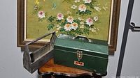 Rustic wood tool caddy and vintage green metal Park toolbox on table with floral painting background