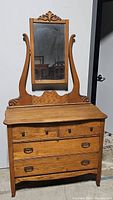 Front view of oak dresser with decorative carved mirror and four drawers (two small, two large).