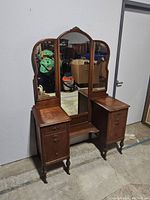 Full view of the vintage vanity showing the tri-fold mirror and two drawer columns with closed drawers.