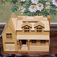 Front view of wooden two-story dollhouse showing roof with handle, dormer windows, front porch, garage door, chimney