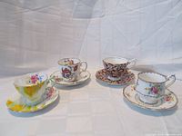 Overall view of four vintage Royal Albert teacup and saucer sets arranged on plain backdrop