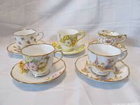Photo of five vintage Royal Albert teacup and saucer sets showing various floral and decorative patterns with gold trim.