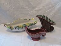 Photo showing three vases, one elongated dish-shaped with multicolor glaze, and two horn-shaped vases in maroon and pink.