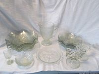 Full set neatly arranged showing all glass pieces on white cloth background including bowls, pitcher, plate, goblet, candlesticks, and sauce bowls