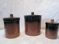 Front view of three ceramic canisters with lids, brown gradient high gloss finish.