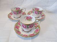Three matching teacup and saucer sets shown together on white backdrop, displaying floral pattern and gold trims.