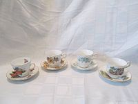 Four Ridgway Potteries Queen Anne teacup and saucer sets with four distinct floral and fruit patterns, shown lined up on a white background.
