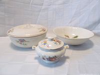 Three Sovereign Potters earthenware pieces including covered dish, serving bowl, and sugar bowl with floral patterns and gold trim